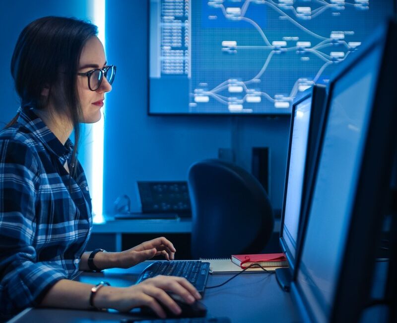 Young female looking at blue computer screens